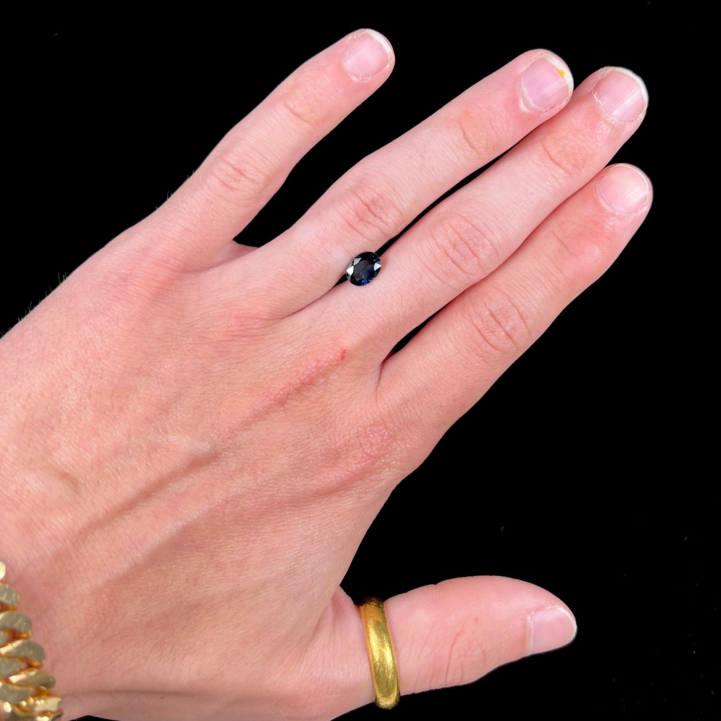 A loose, faceted oval cut natural blue sapphire gemstone.