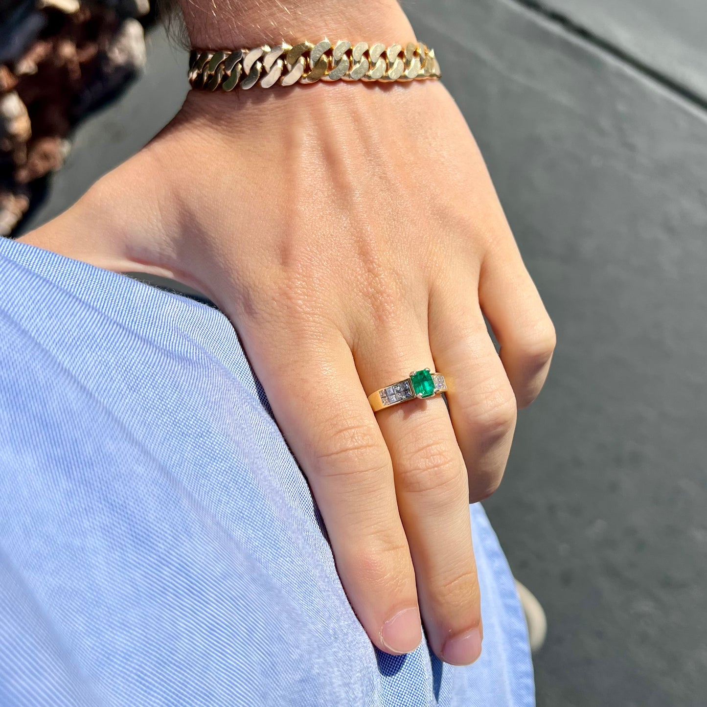 An 18 karat yellow gold ladies' emerald ring, channel set with princess cut diamonds.