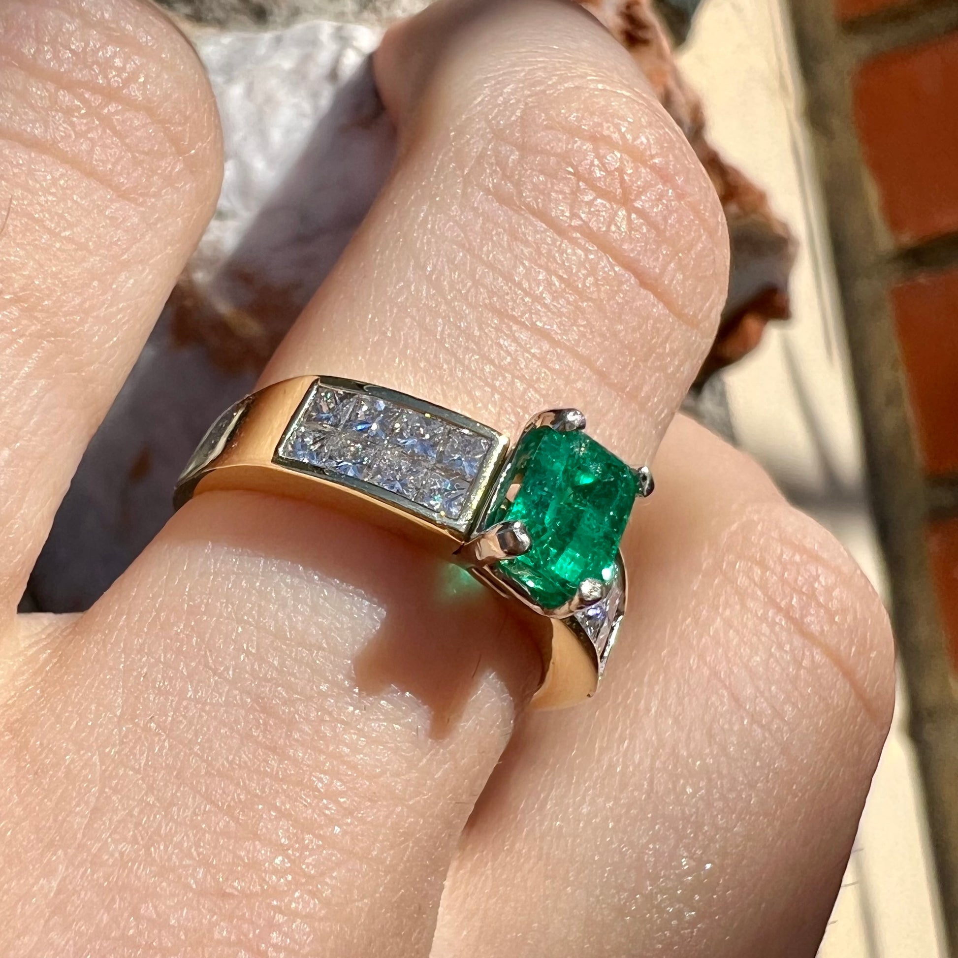 An 18 karat yellow gold ladies' emerald ring, channel set with princess cut diamonds.
