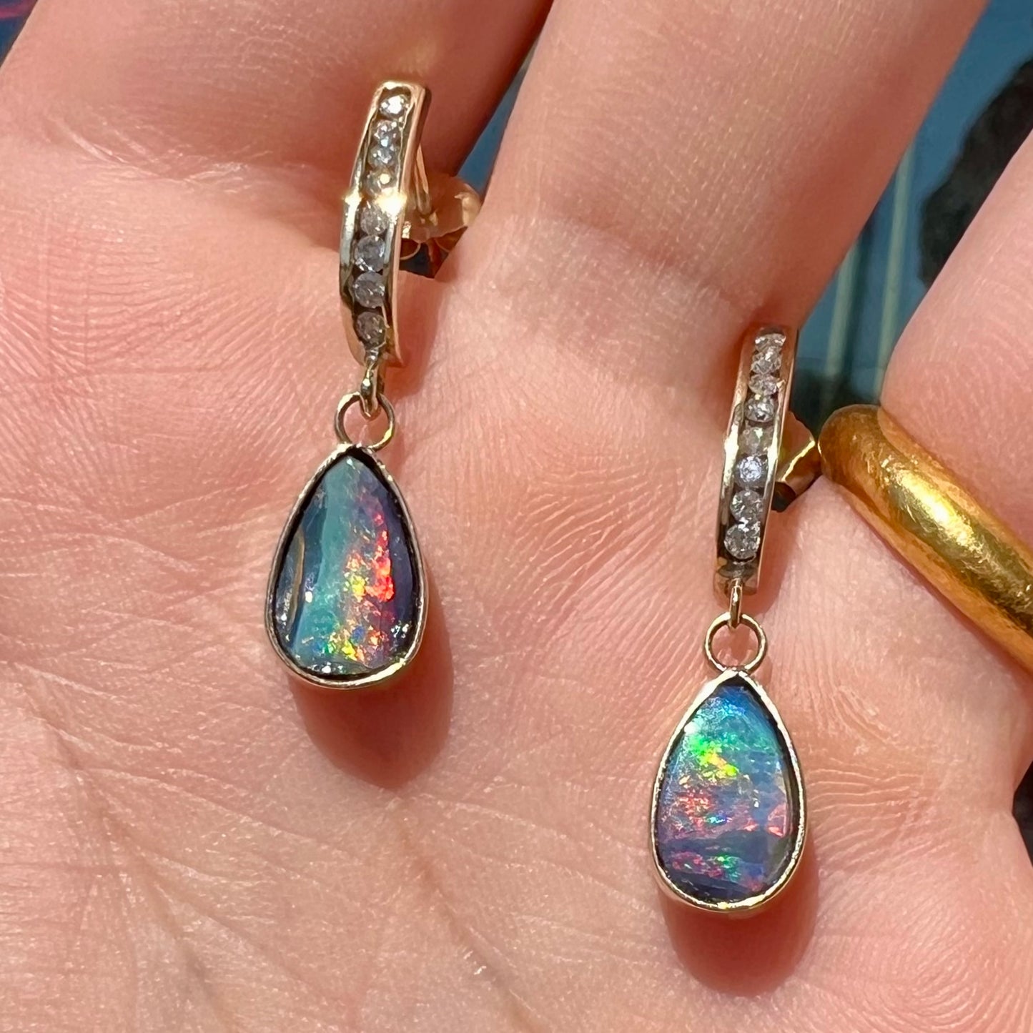 A pair of yellow gold dangle earrings set with natural pear shaped boulder opals and diamonds.