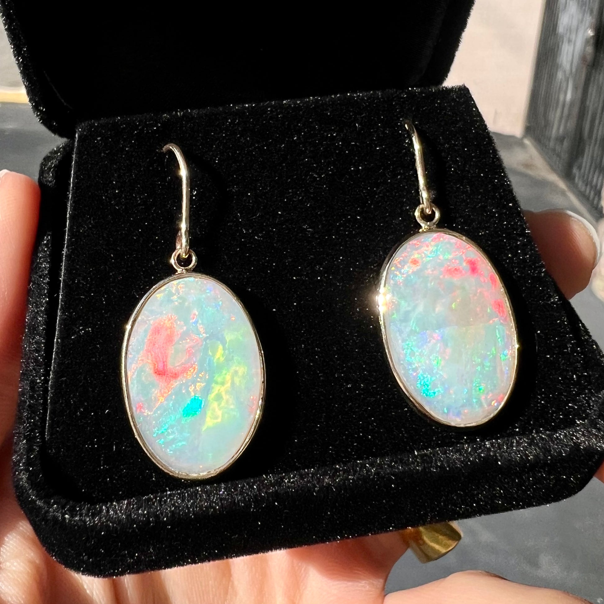 A pair of yellow gold earrings bezel set with oval cabochon cut natural opal stones.