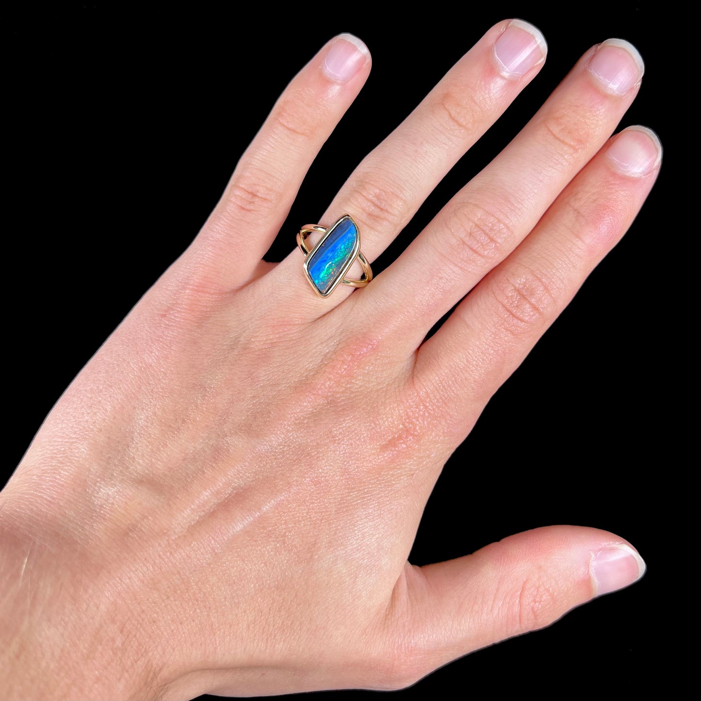A ladies' split shank gold ring bezel set with a natural, Australian black boulder opal.