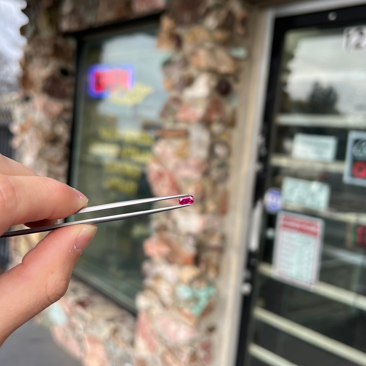 A loose, purplish red natural ruby gemstone. The stone is emerald cut.
