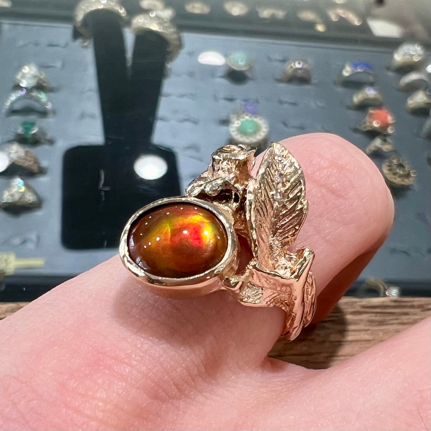 A ladies' yellow gold flower style ring set with an oval cabochon cut fire agate and diamond accents.