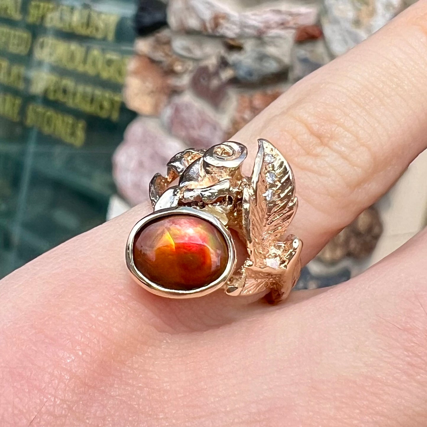 A ladies' yellow gold flower style ring set with an oval cabochon cut fire agate and diamond accents.