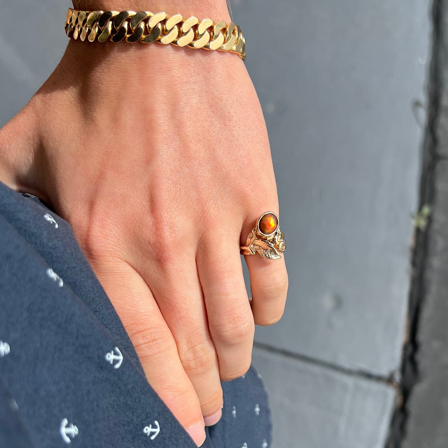 A ladies' yellow gold flower style ring set with an oval cabochon cut fire agate and diamond accents.