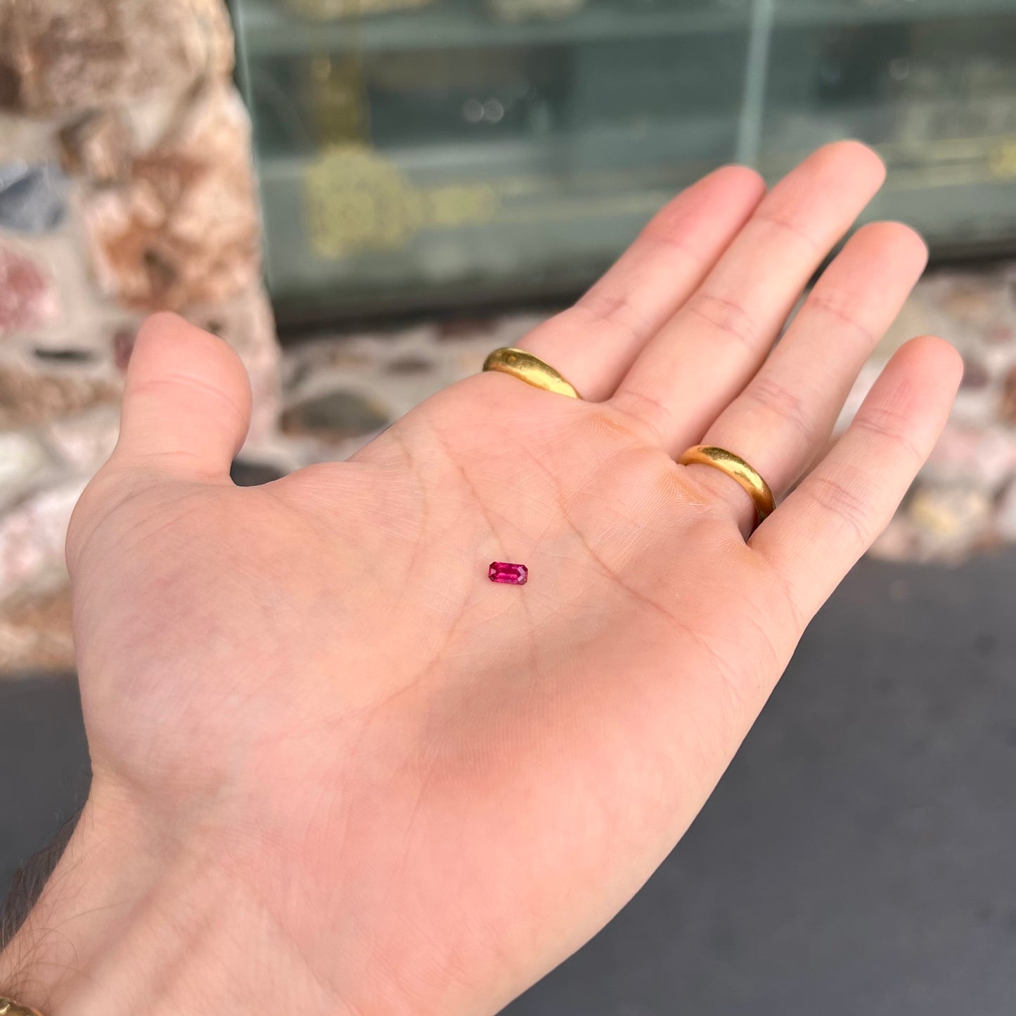 A loose, purplish red natural ruby gemstone. The stone is emerald cut.