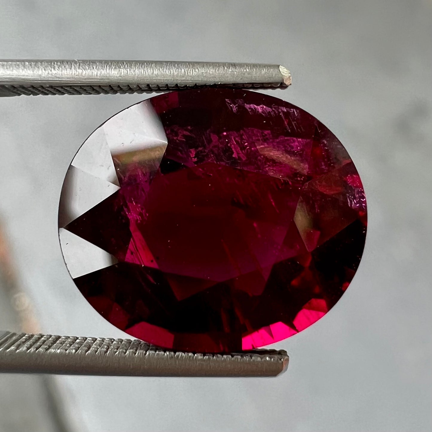 A loose, oval cut purplish red rubellite tourmaline stone.