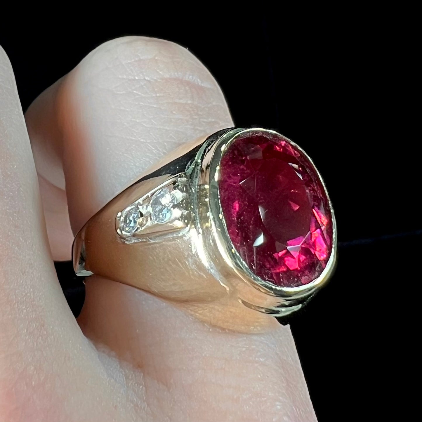 A men's yellow gold ring set with an oval cut rubellite tourmaline with diamond accents.