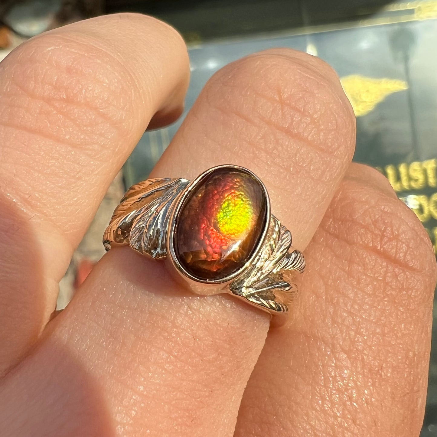 A unisex oval cabochon cut fire agate ring cast in yellow gold. The stone flashes green and red colors.