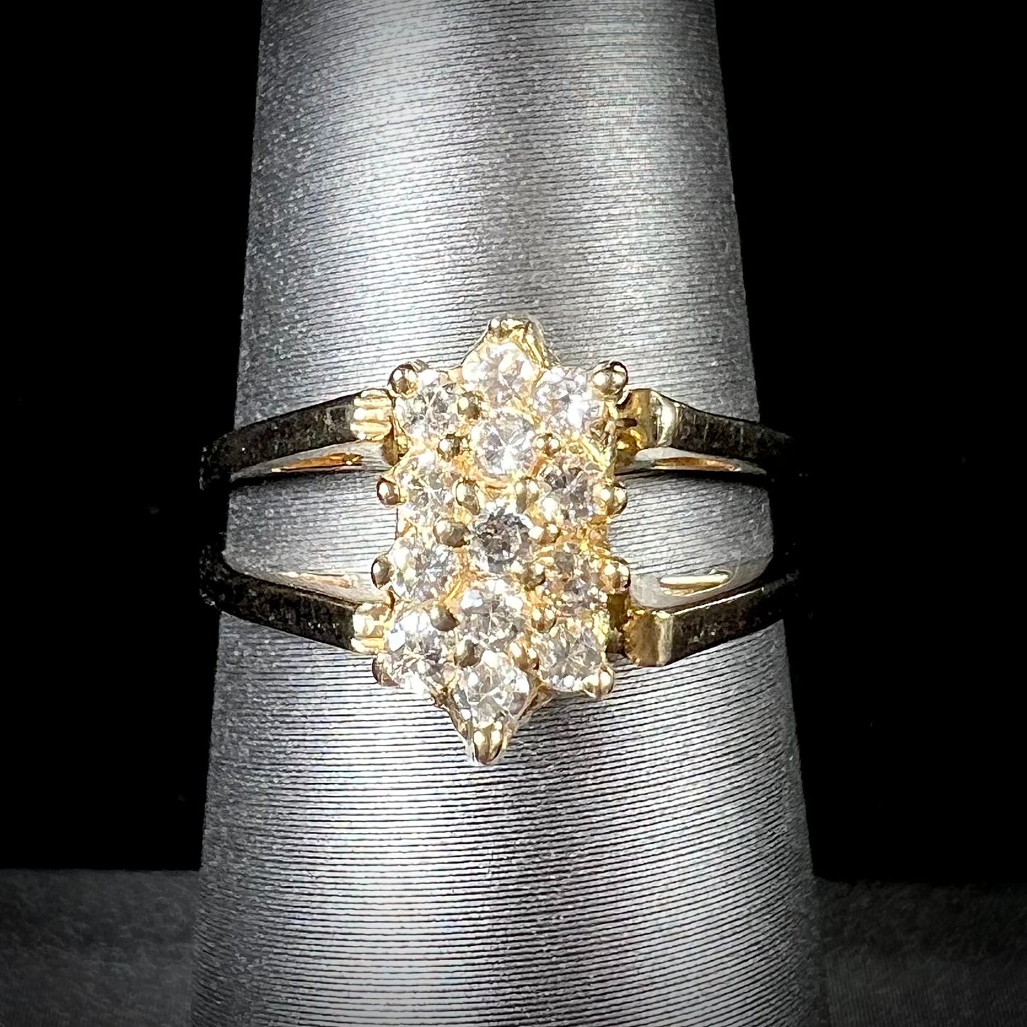 A yellow gold reversible gemstone flip ring. One side of the ring shows a green gemstone, the other shows a cluster of cubic zirconia.