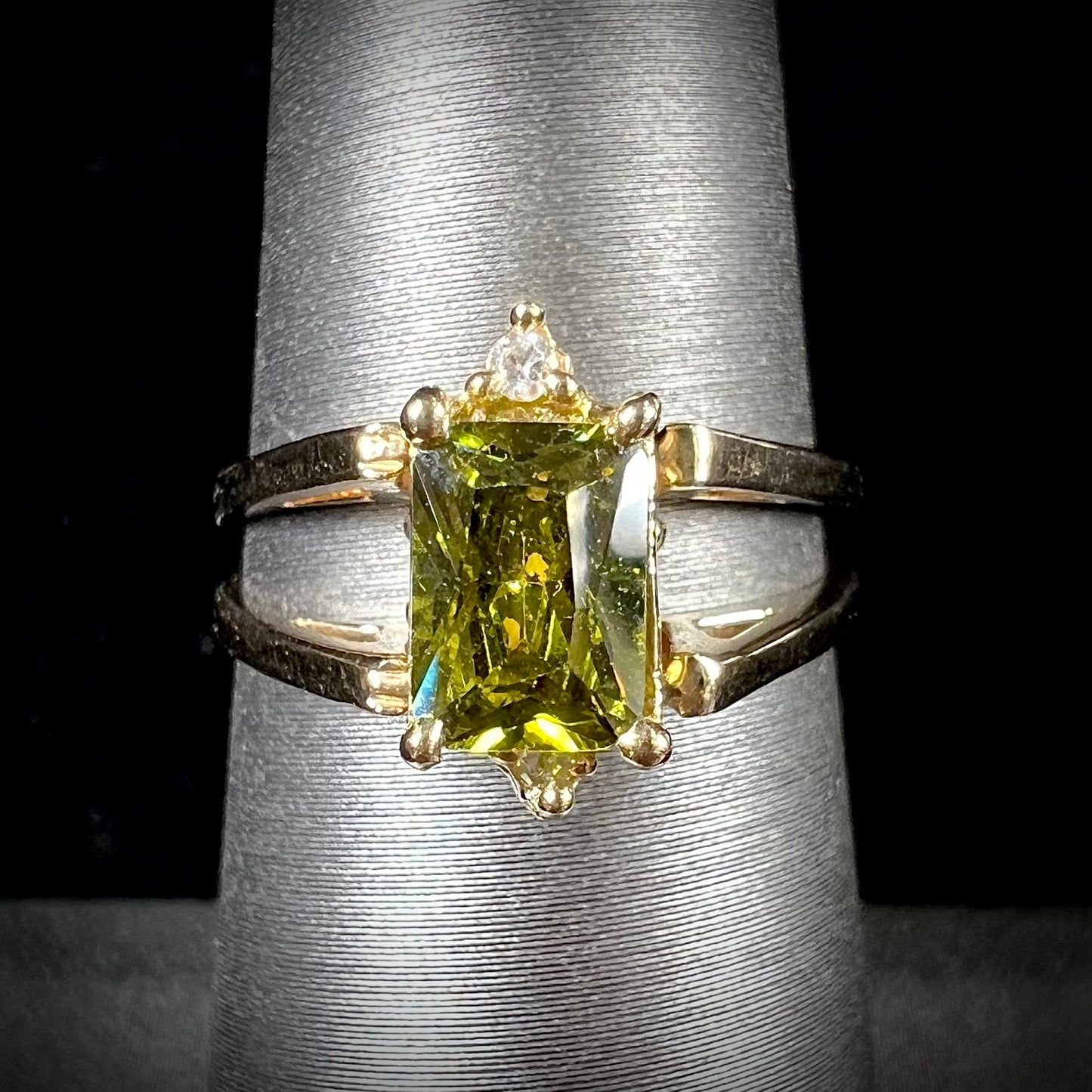 A yellow gold reversible gemstone flip ring. One side of the ring shows a green gemstone, the other shows a cluster of cubic zirconia.