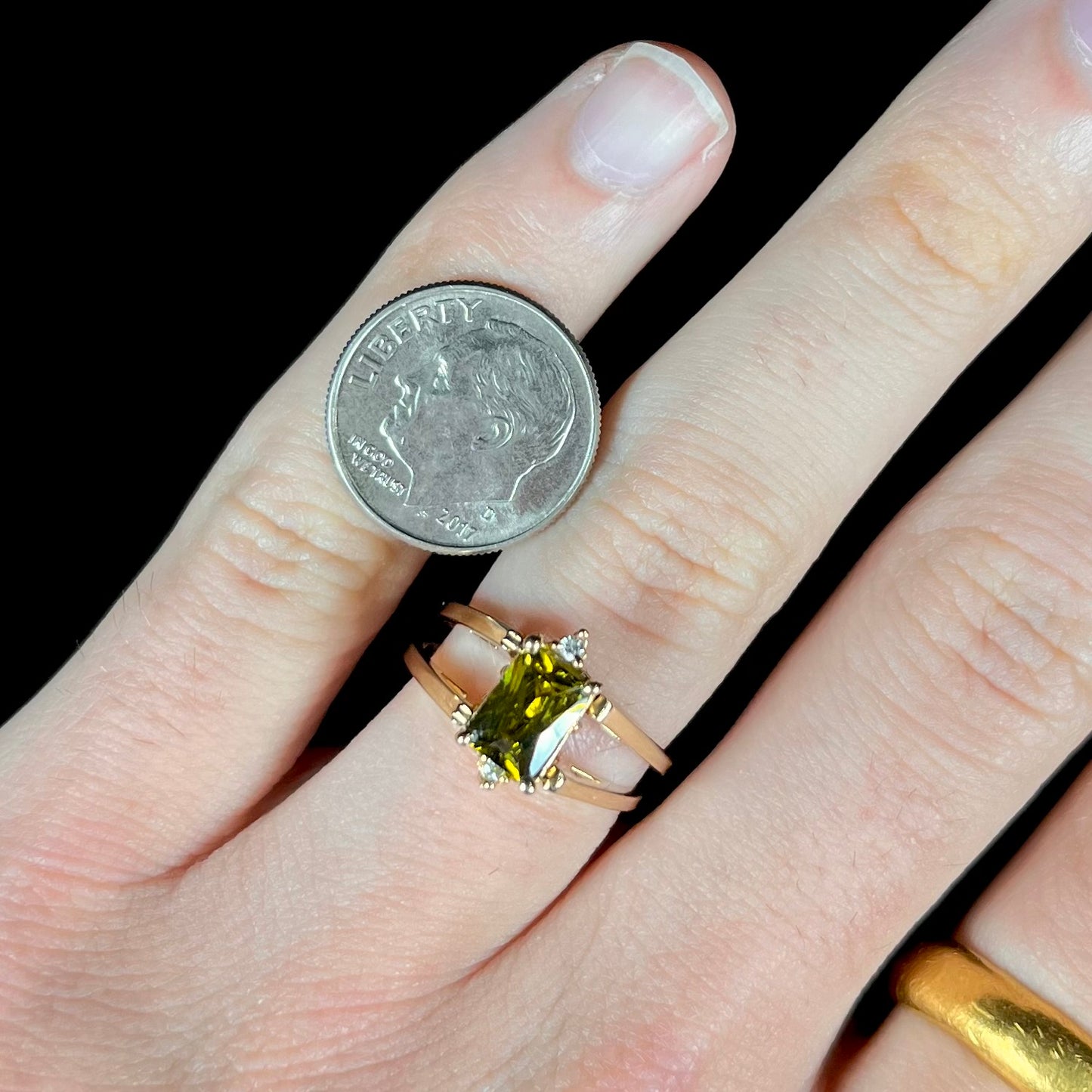 A yellow gold reversible gemstone flip ring. One side of the ring shows a green gemstone, the other shows a cluster of cubic zirconia.