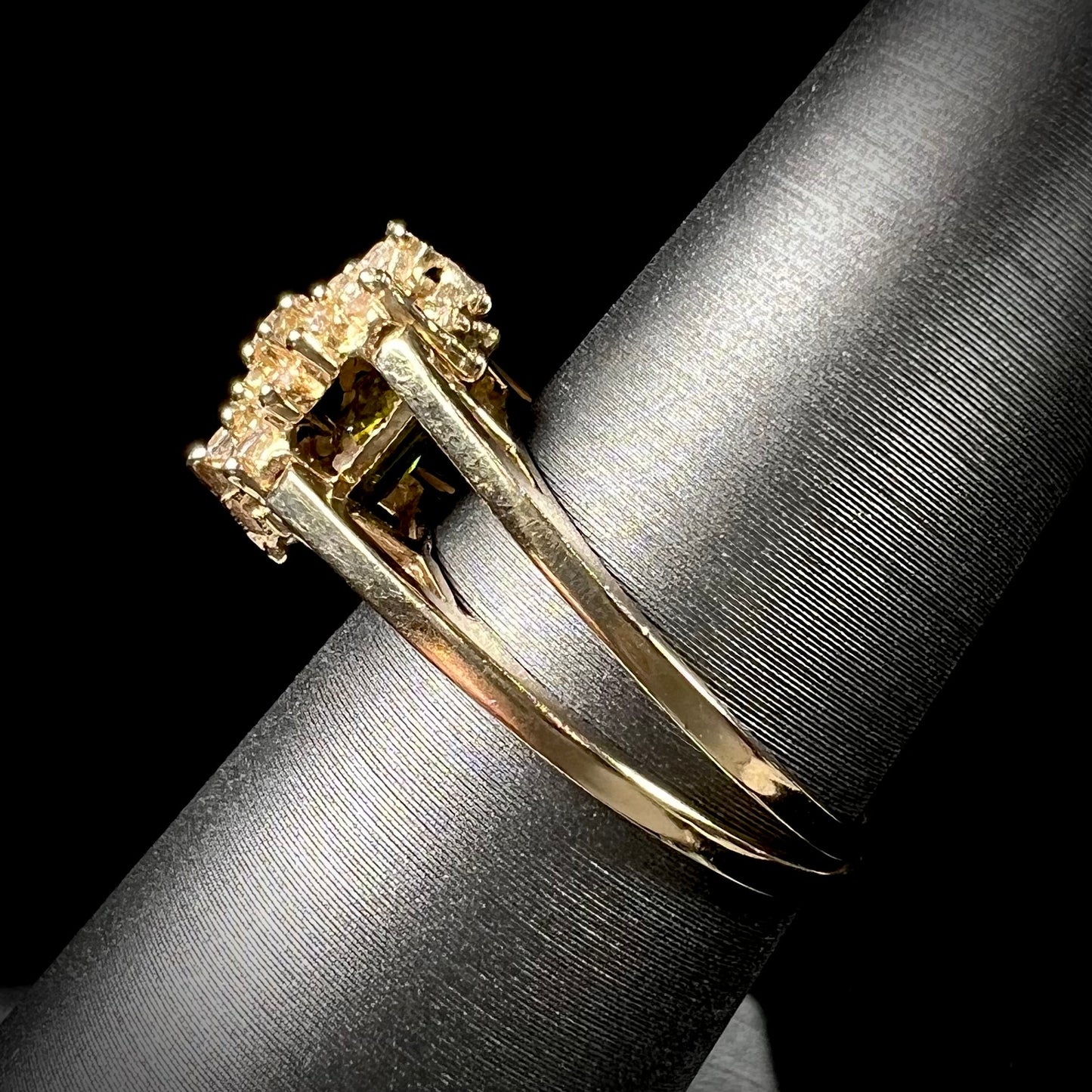 A yellow gold reversible gemstone flip ring. One side of the ring shows a green gemstone, the other shows a cluster of cubic zirconia.