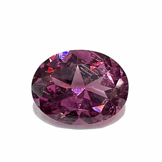 A loose, faceted oval cut purple rhodolite garnet gemstone.