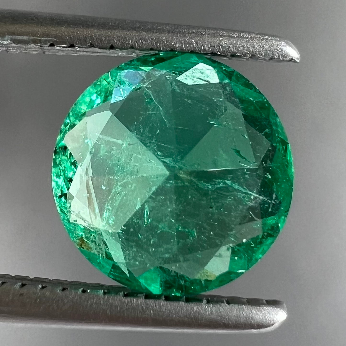 A loose, round brilliant cut natural emerald stone.