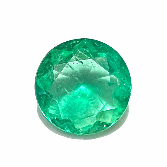 A loose, round brilliant cut natural emerald stone.
