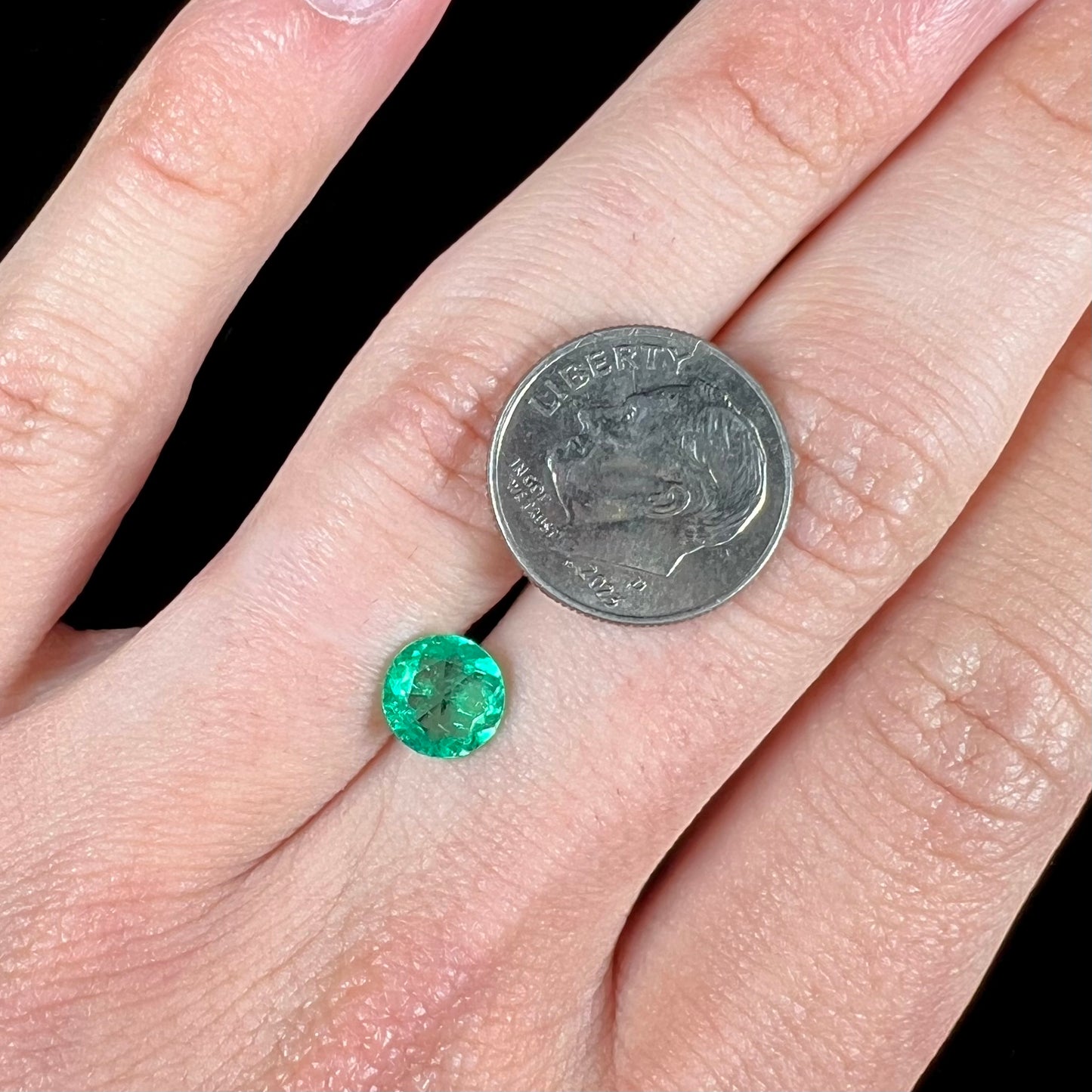 A loose, round brilliant cut natural emerald stone.
