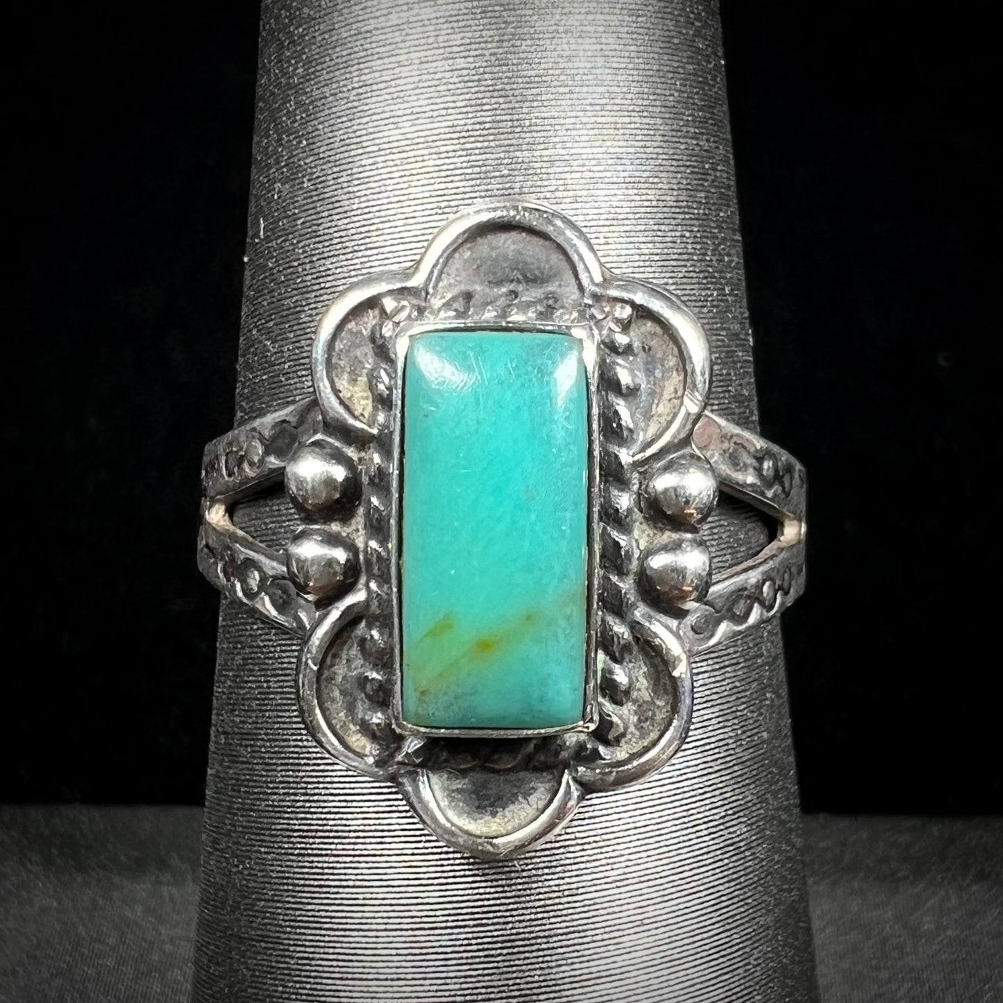 A ladies' silver ring stamped with Southwest style designs and set with a rectangular cabochon cut Royston turquoise stone.