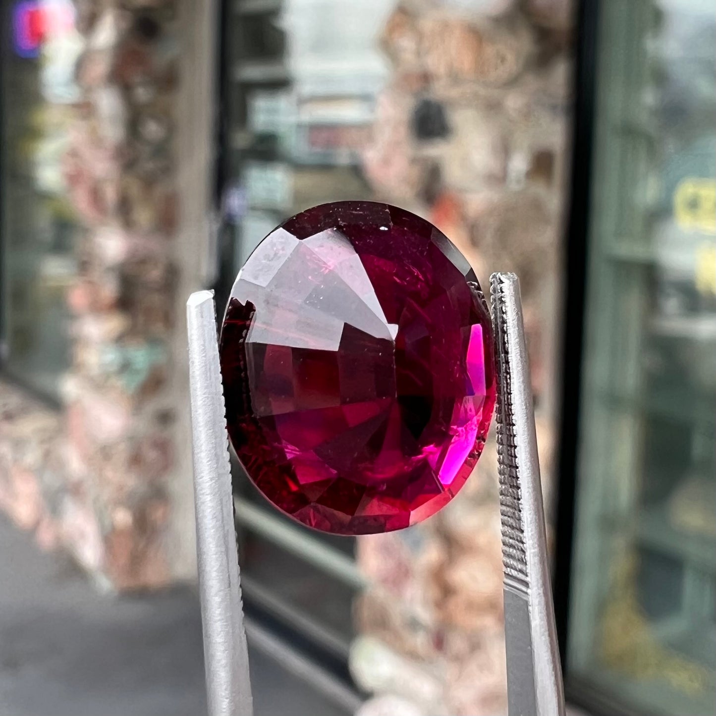 A loose, oval cut purplish red rubellite tourmaline stone.