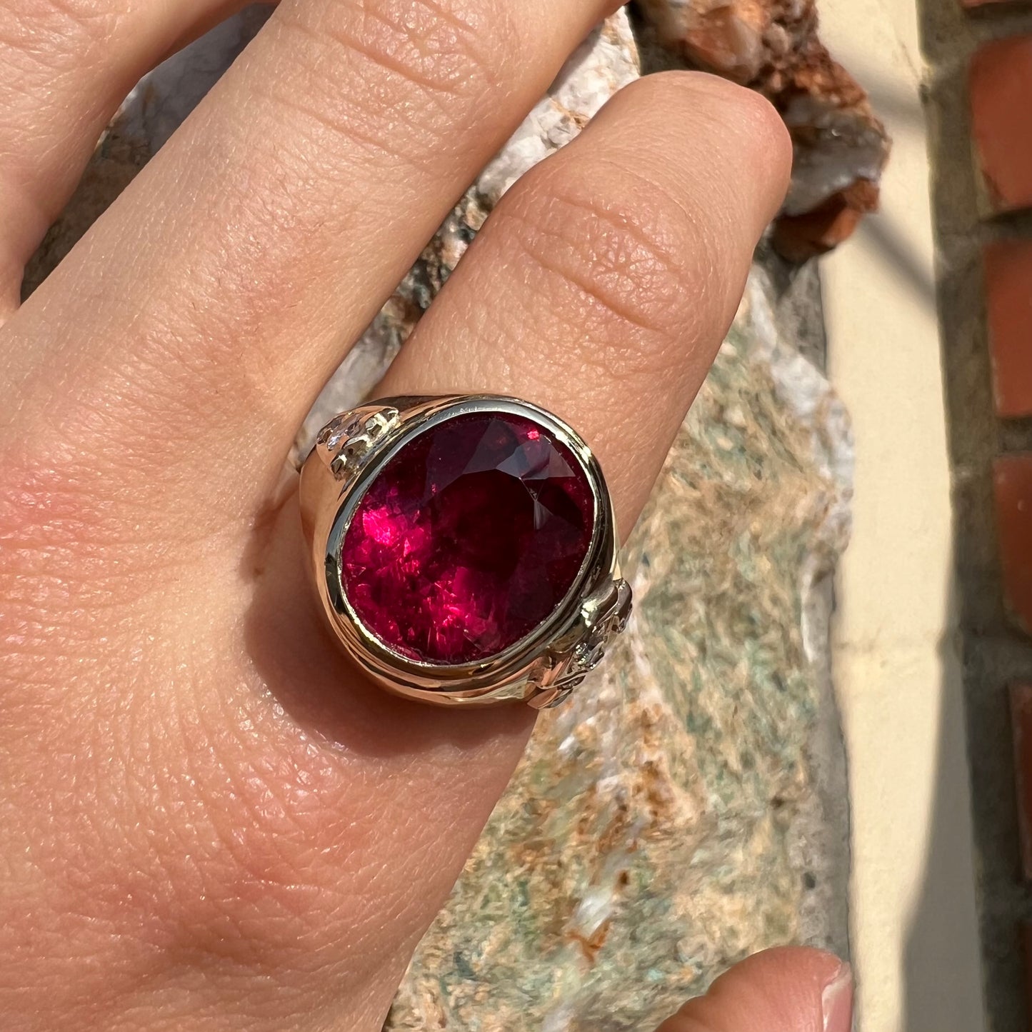 A men's yellow gold ring set with an oval cut rubellite tourmaline with diamond accents.