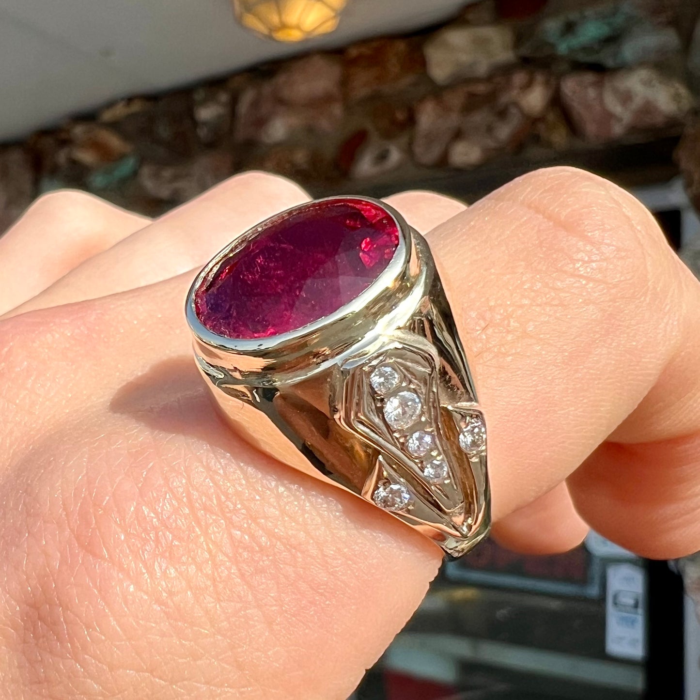 A men's yellow gold ring set with an oval cut rubellite tourmaline with diamond accents.