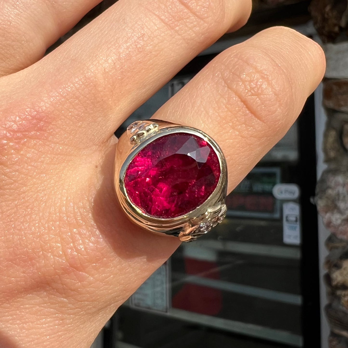 A men's yellow gold ring set with an oval cut rubellite tourmaline with diamond accents.