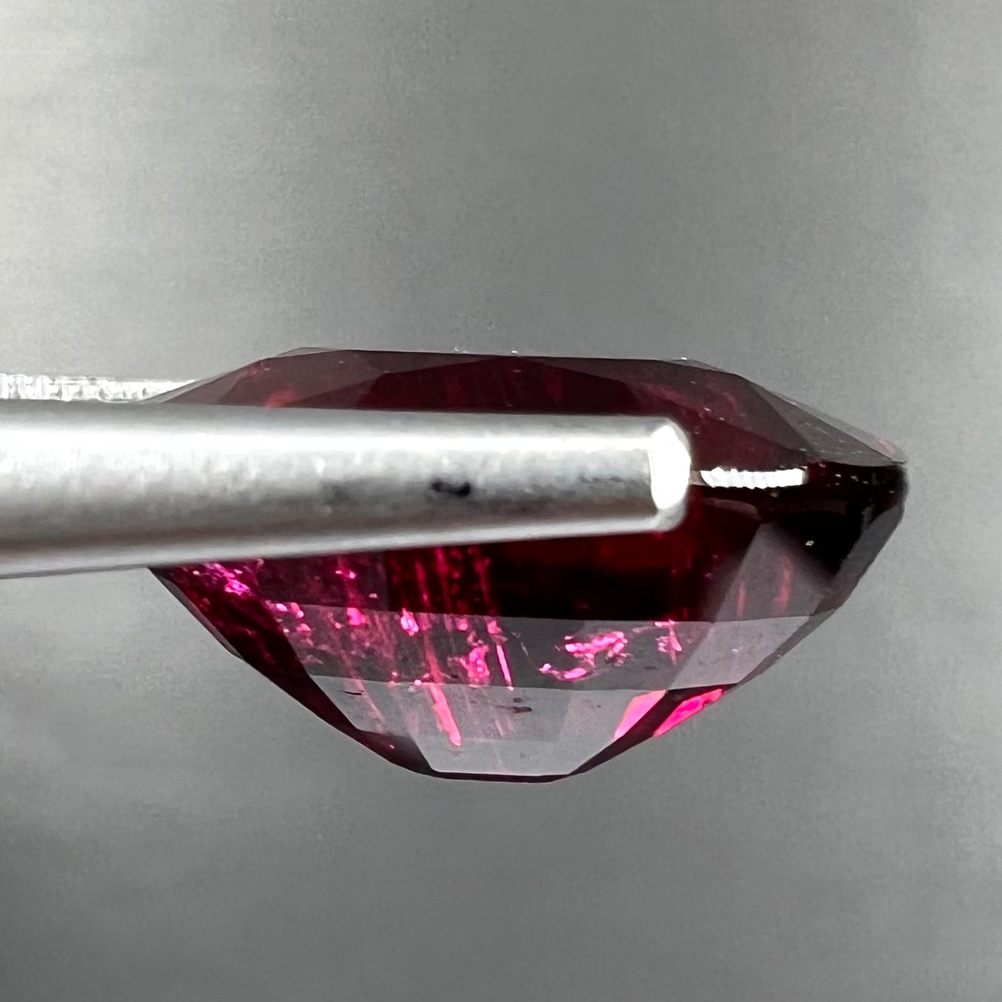 A loose, oval cut purplish red rubellite tourmaline stone.