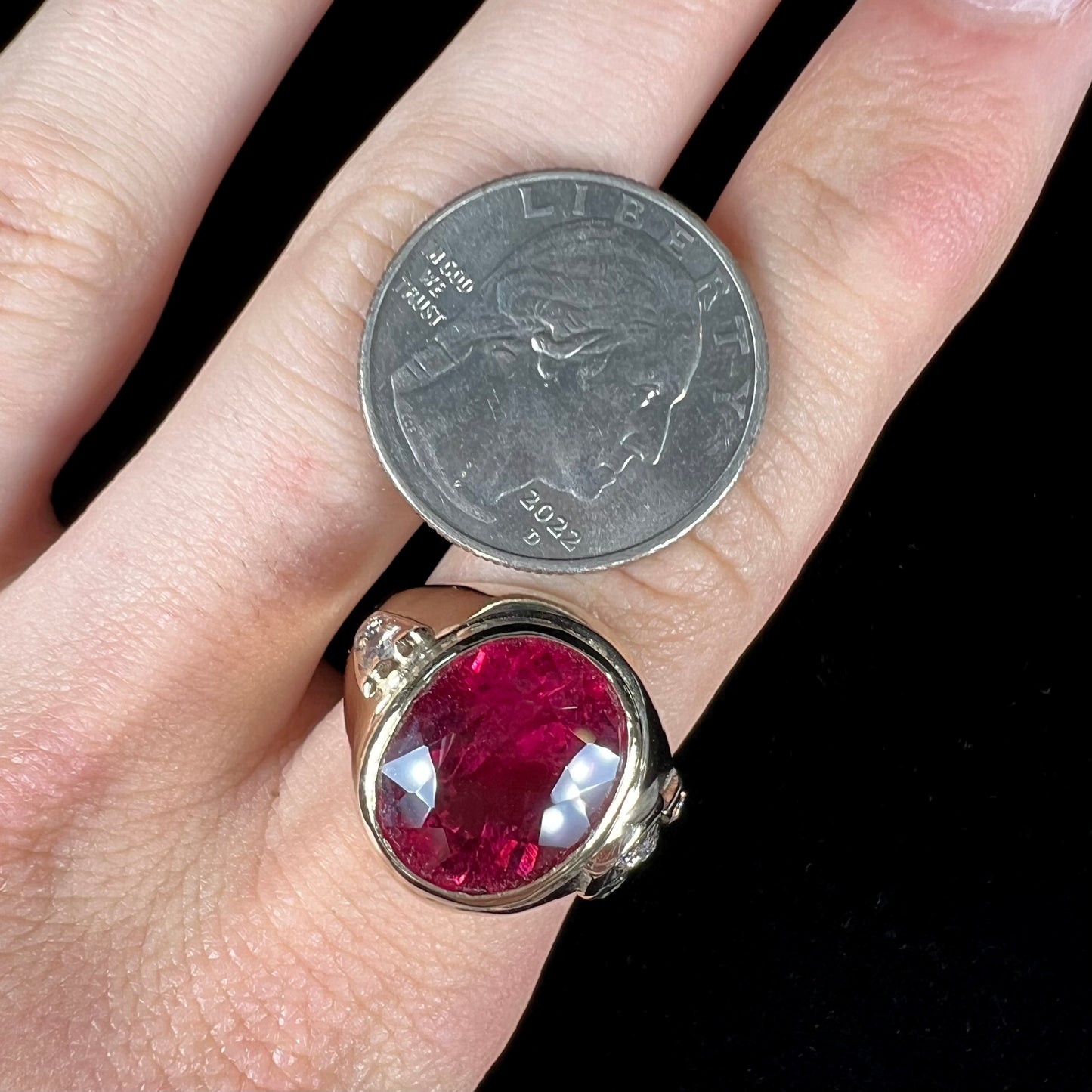 A men's yellow gold ring set with an oval cut rubellite tourmaline with diamond accents.