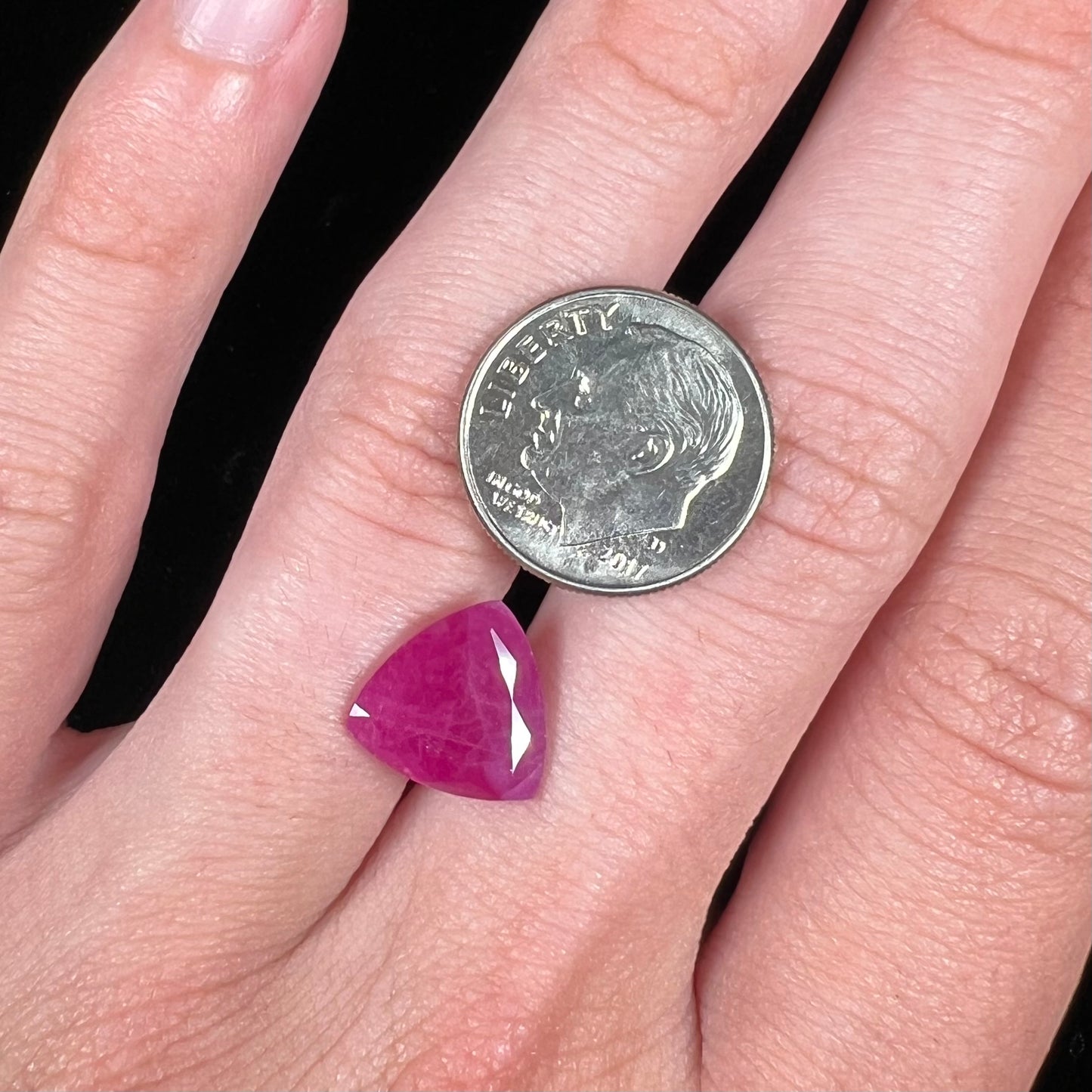 A loose, faceted trillion cut, natural, commercial grade ruby gemstone. The stone is purplish red color.