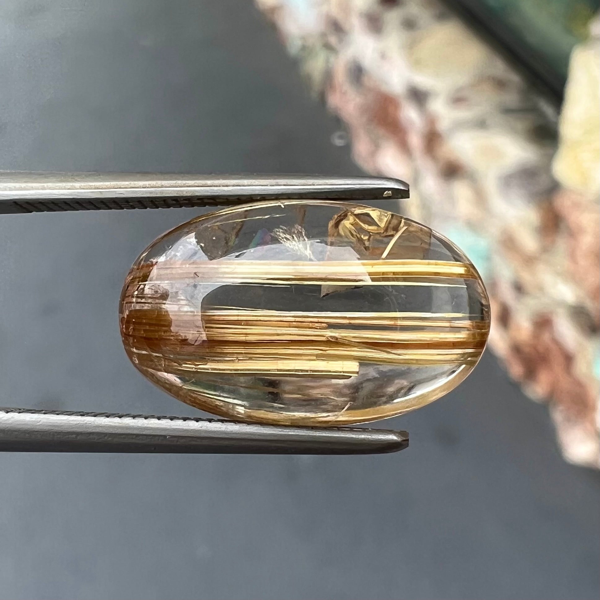 A loose, oval cabochon cut cat's eye golden rutilated quartz stone.