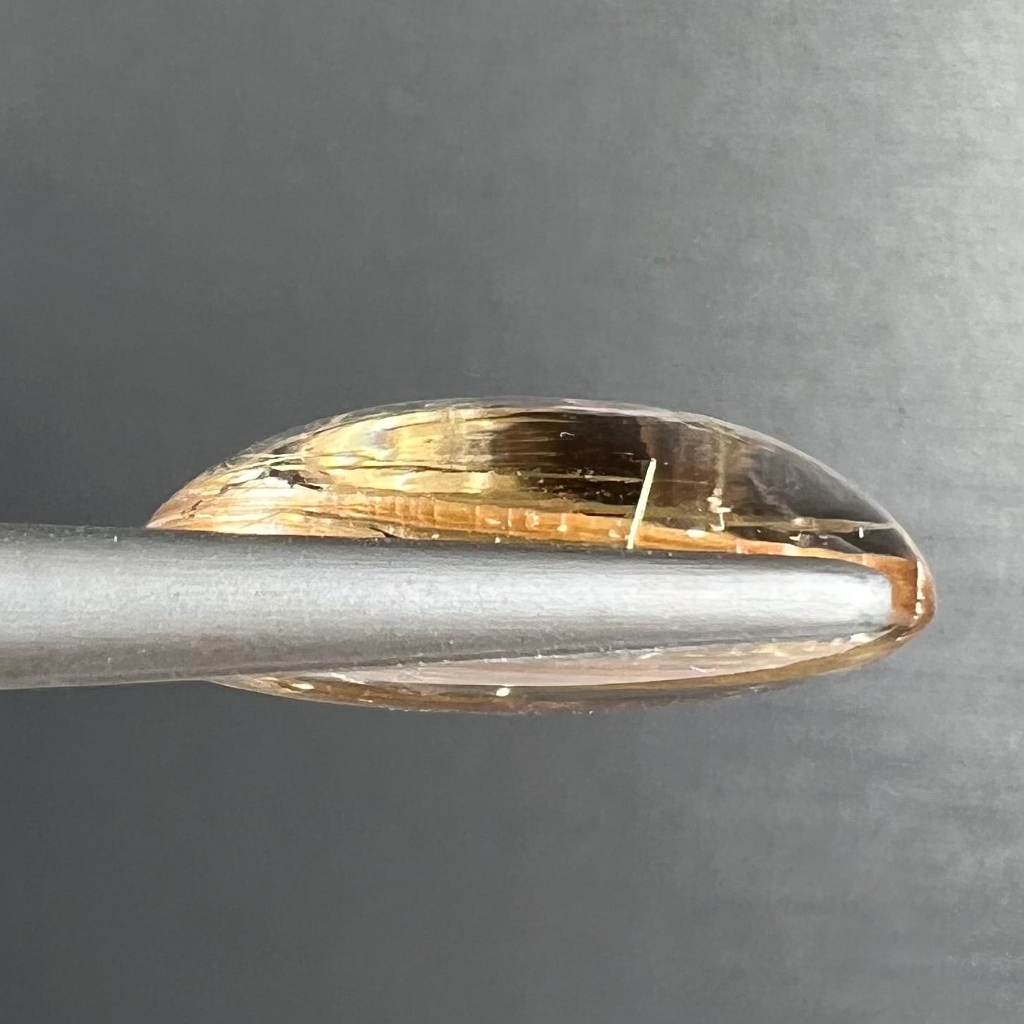 A loose, oval cabochon cut cat's eye golden rutilated quartz stone.