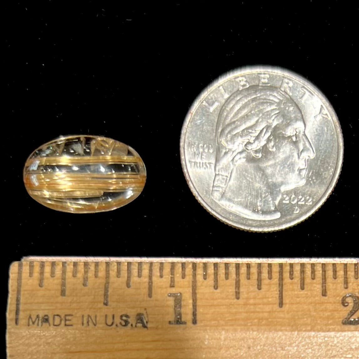 A loose, oval cabochon cut cat's eye golden rutilated quartz stone.