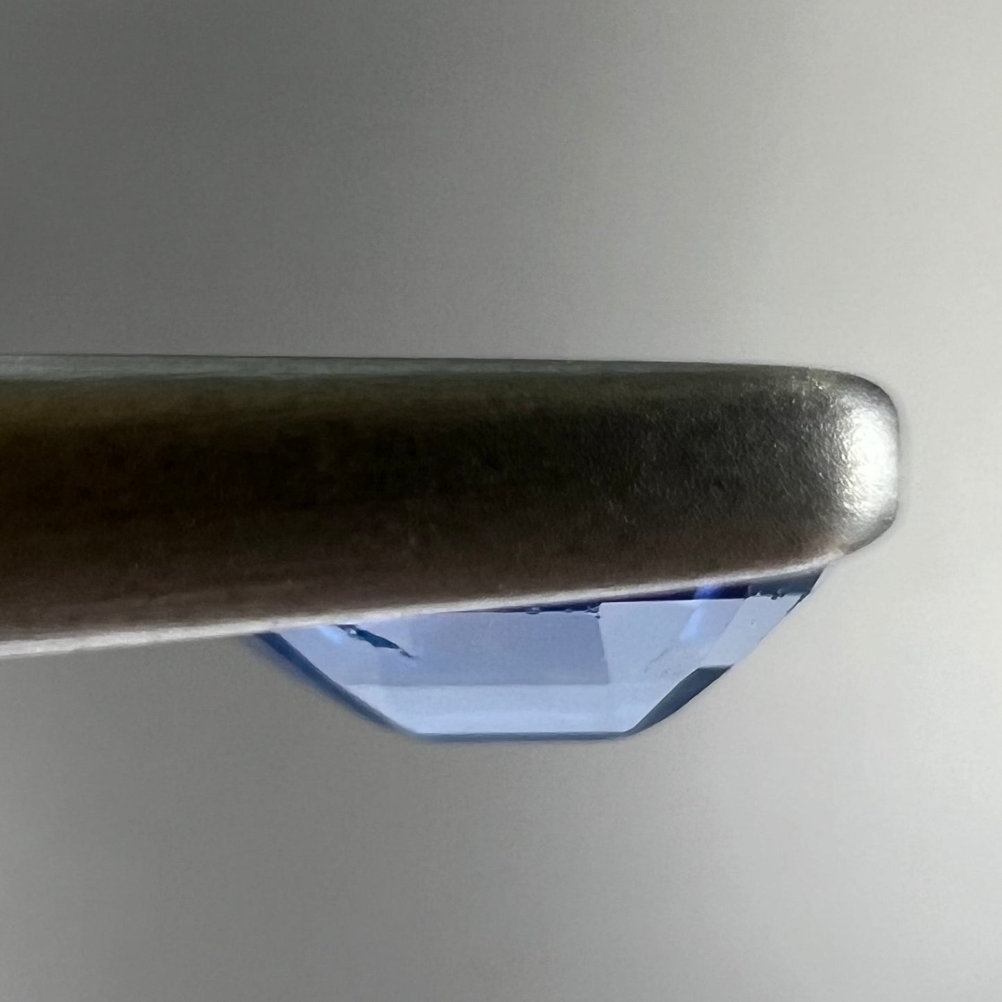 A loose, faceted oval cut natural blue sapphire. The color is a dark cornflower blue.