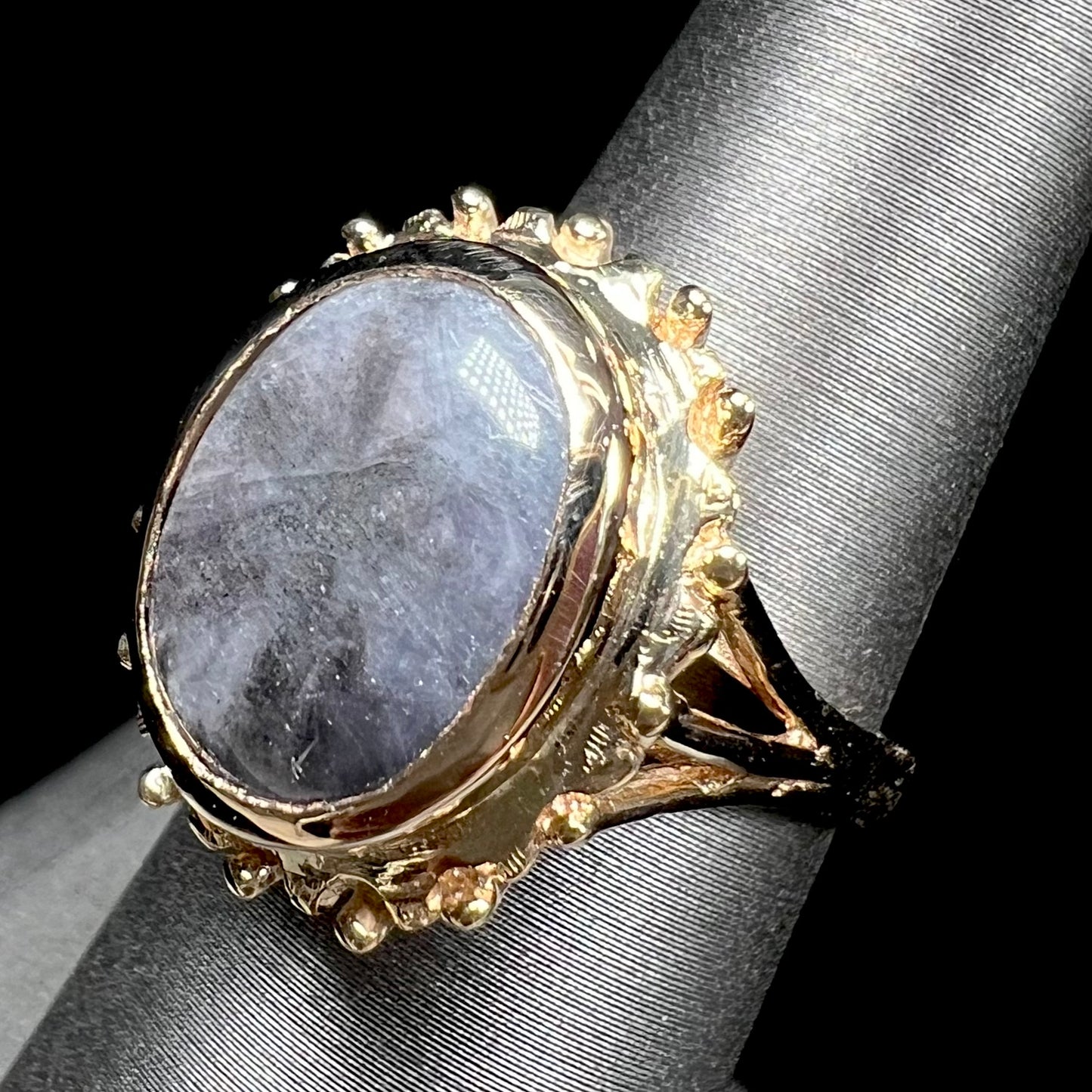 A ladies' yellow gold solitaire ring mounted with a gray trapiche star sapphire.