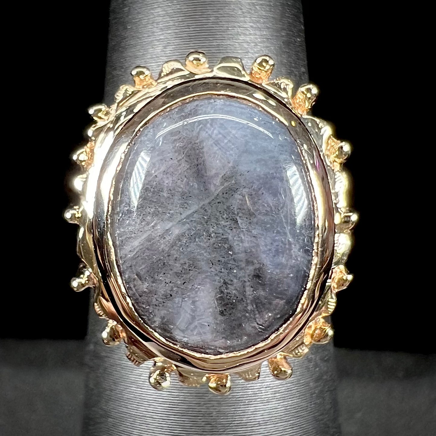 A ladies' yellow gold solitaire ring mounted with a gray trapiche star sapphire.