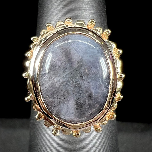 A ladies' yellow gold solitaire ring mounted with a gray trapiche star sapphire.