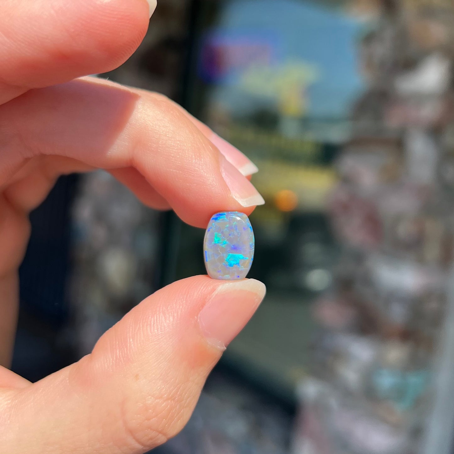 A loose, barrel shaped semi-black opal from Lightning Ridge, Australia. The opal has blue colors.