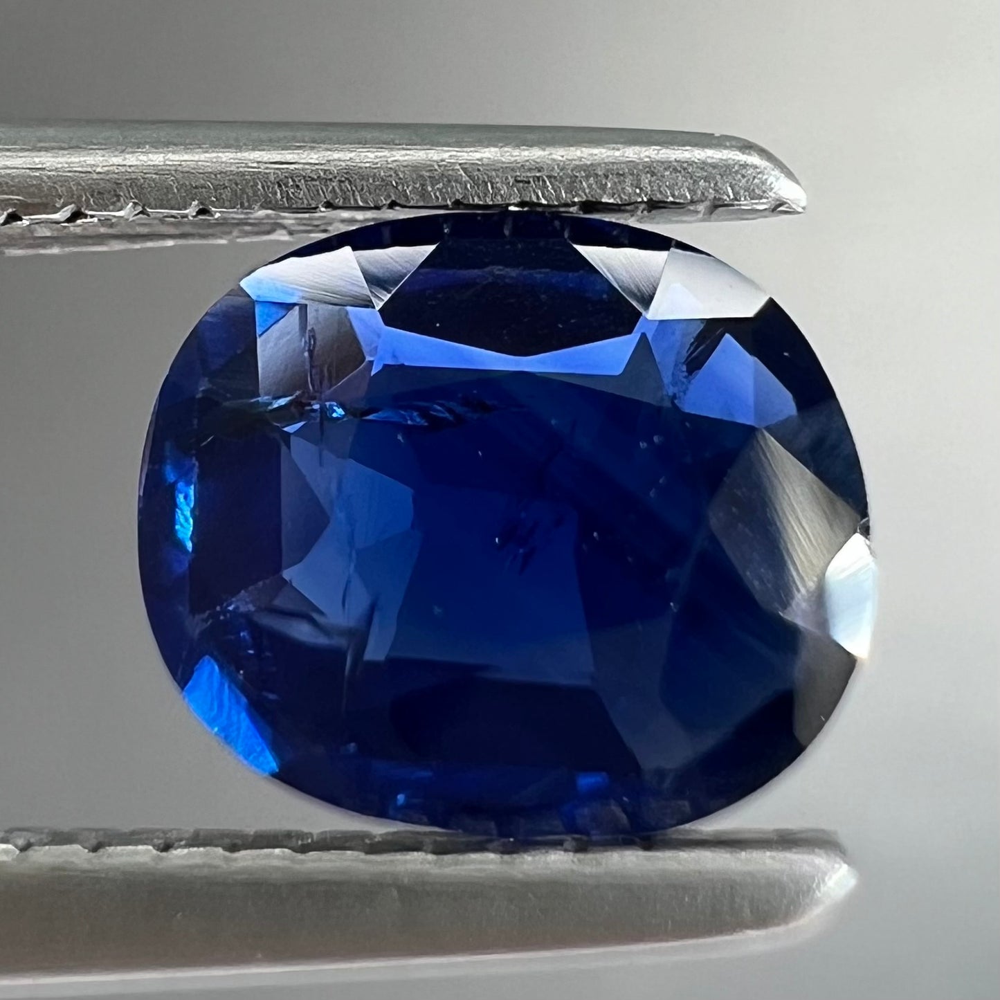 A loose, faceted oval cut dark blue natural sapphire stone.