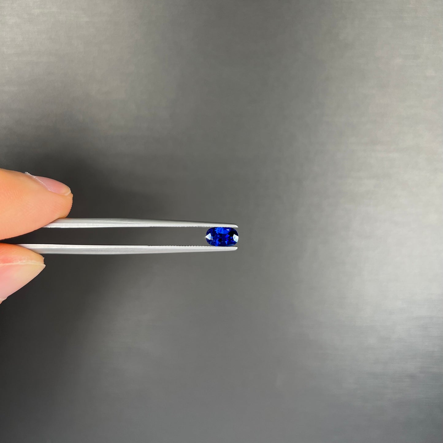 A loose, elongated oval cut blue sapphire gemstone.