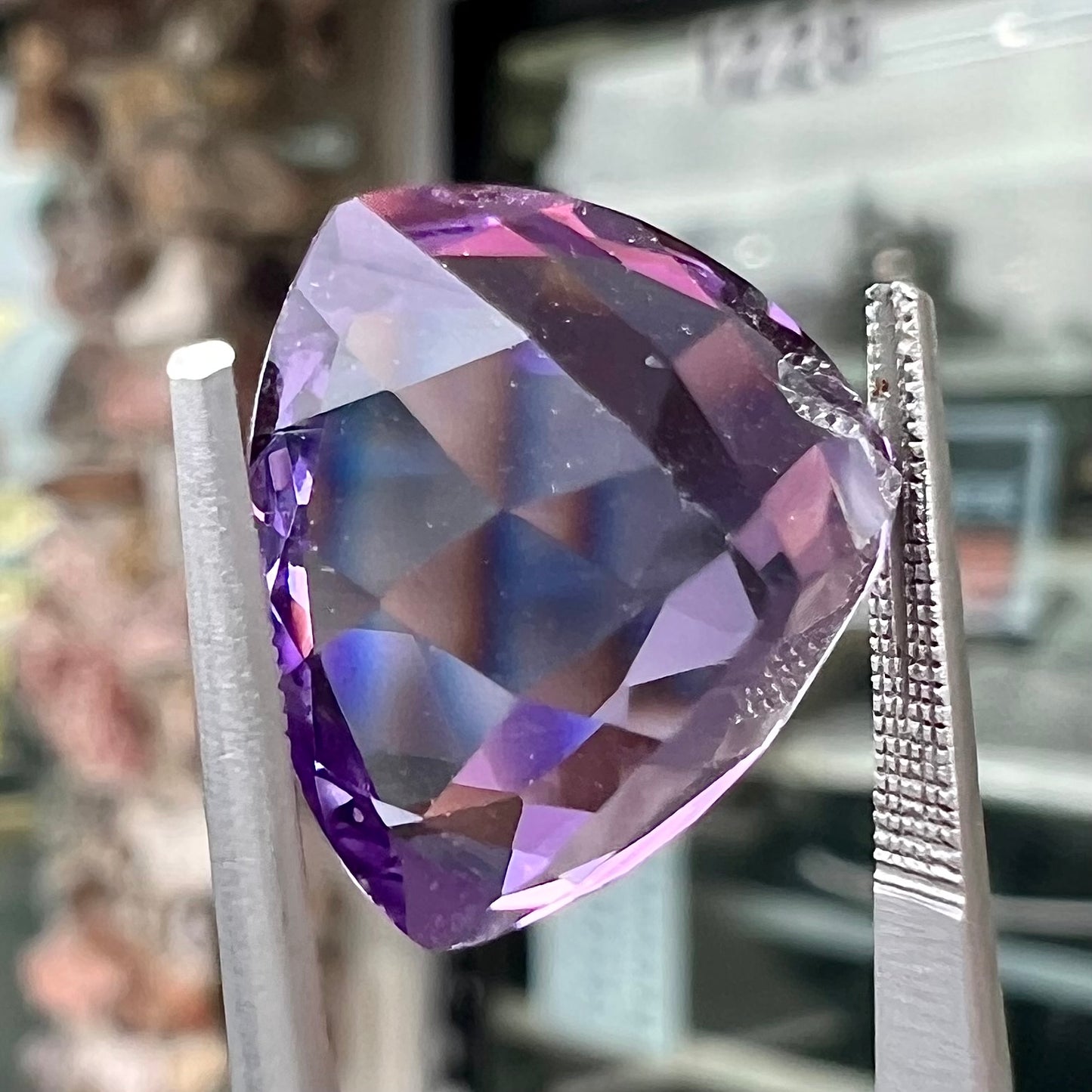 A loose, faceted trillion cut amethyst gemstone.