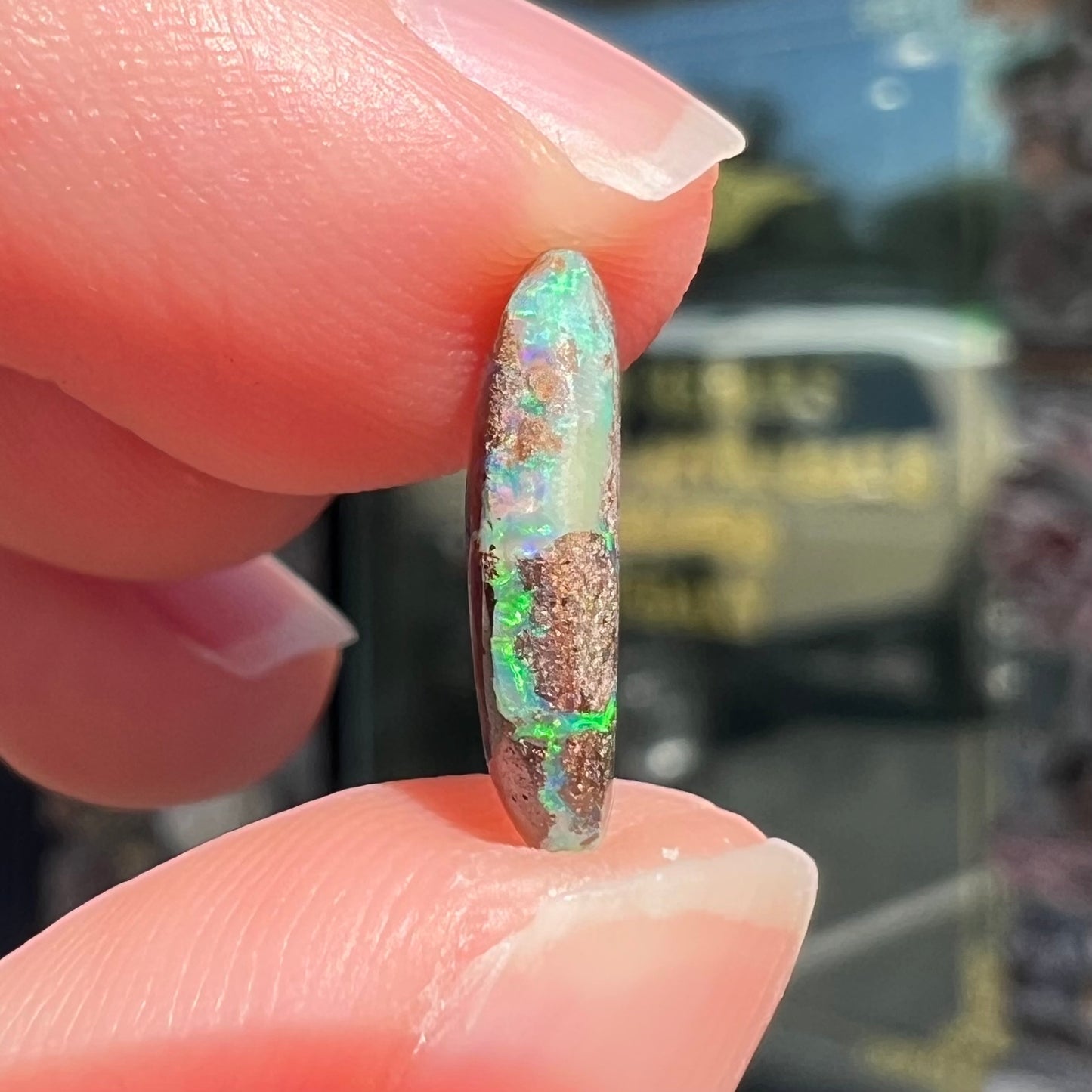 A loose, oval cabochon cut Koroit boulder opal stone. The opal has a bright green color.