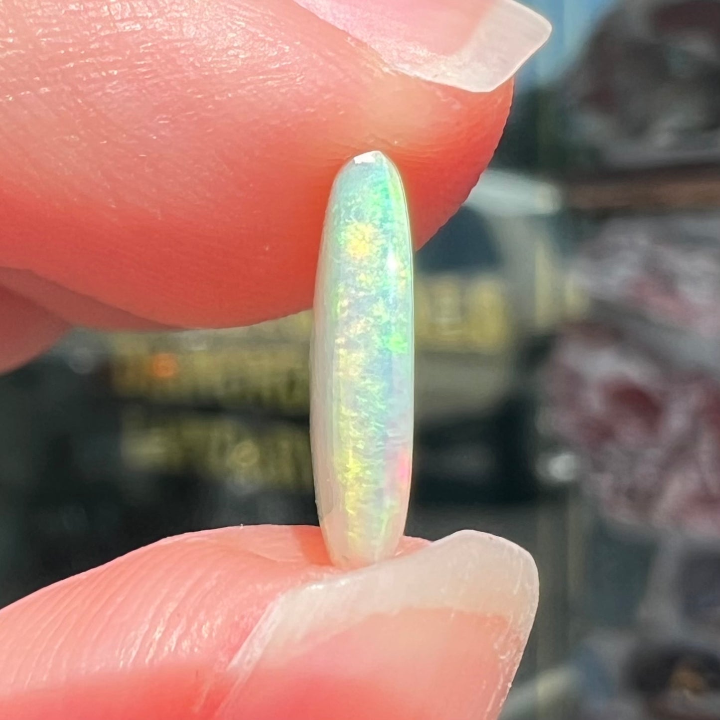 A loose, oval cabochon cut crystal opal from Coober Pedy, Australia. The opal has green and blue colors.