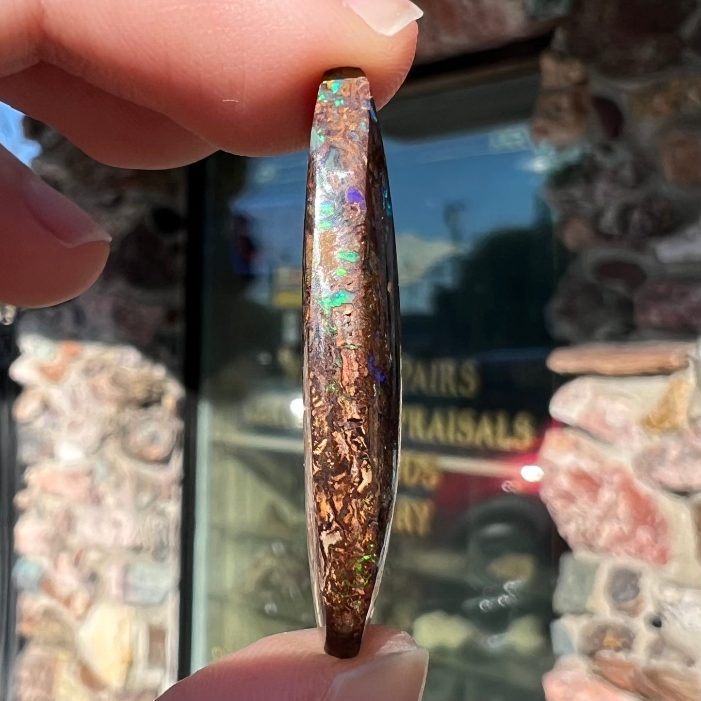 A pear shaped boulder opal stone from Koroit, Australia. The opal has blue and green flashes.