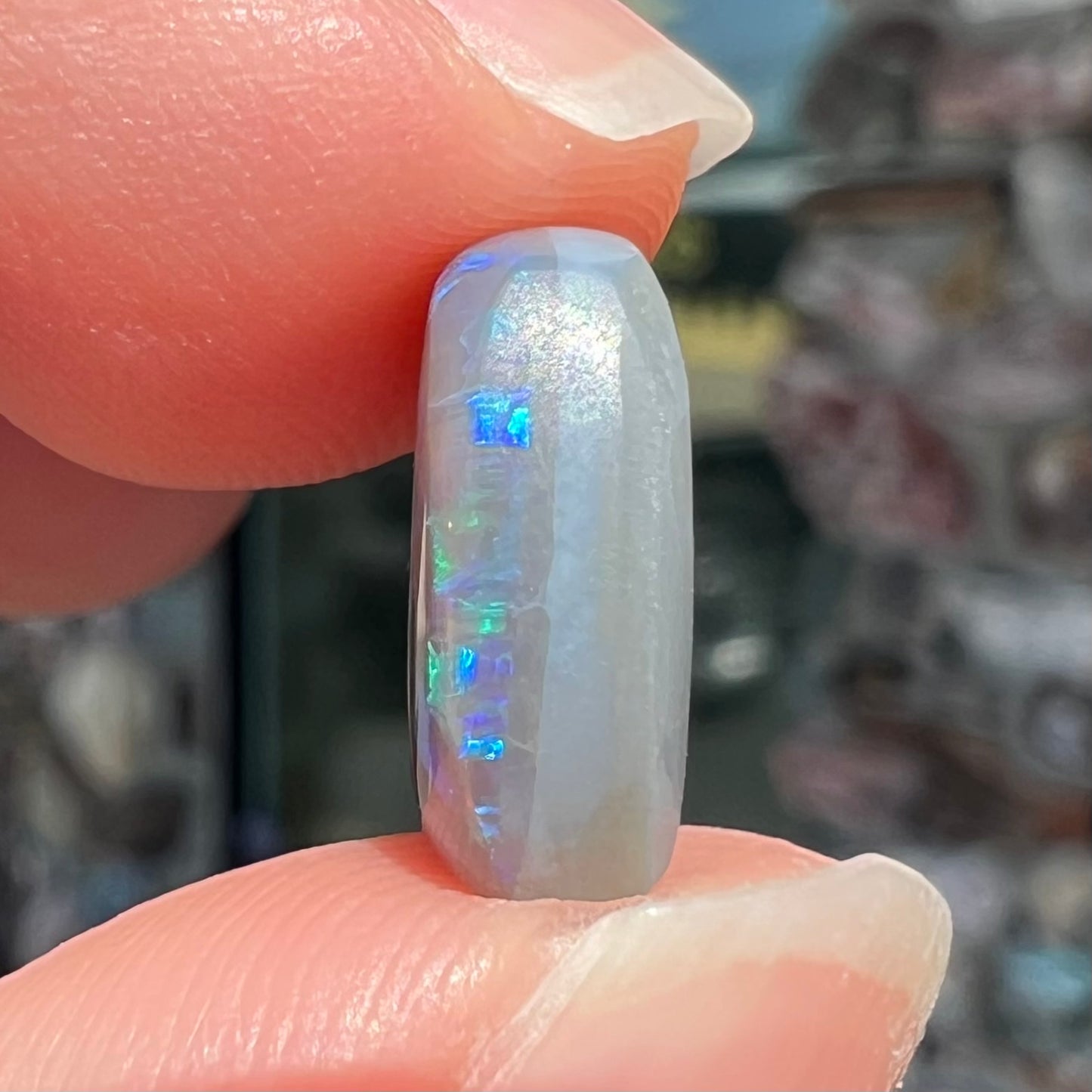 A loose, barrel shaped semi-black opal from Lightning Ridge, Australia. The opal has blue colors.