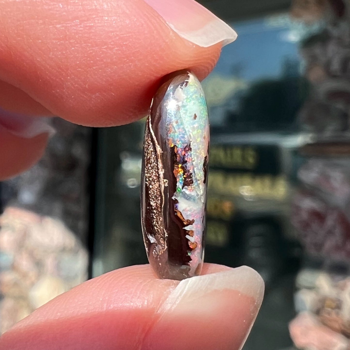 An oval cabochon cut boulder opal stone from Koroit, Australia. The opal has a white body tone.