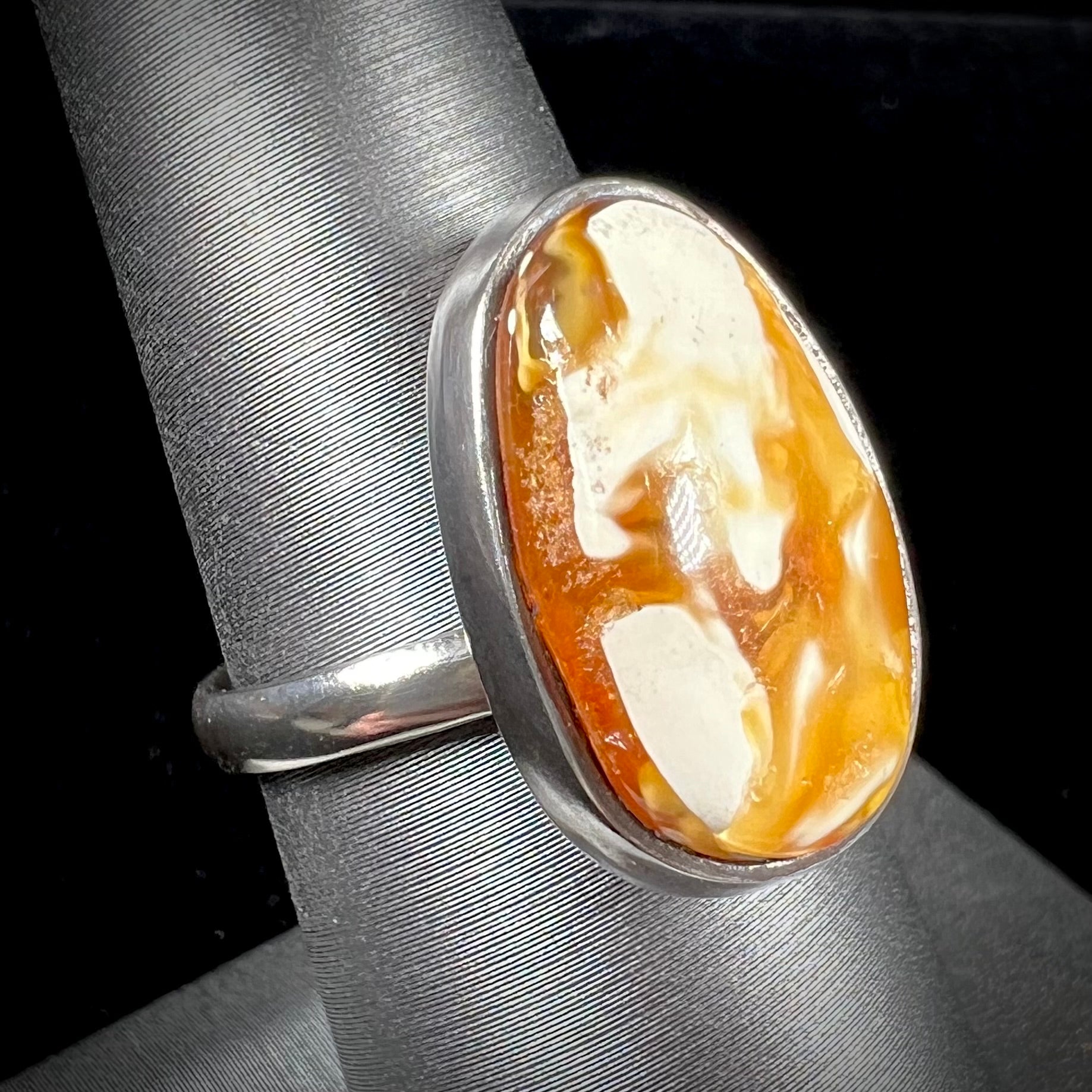 An adjustable sterling silver solitaire ring set with a cabochon cut butterscotch amber stone.