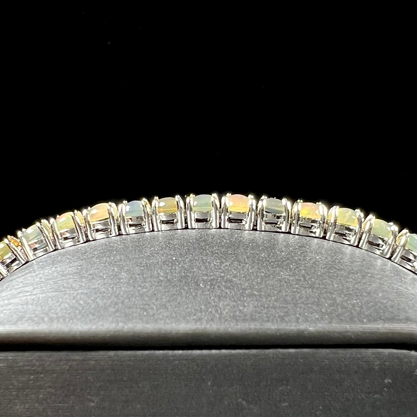 A ladies' sterling silver tennis style bracelet set with natural orange yellow Mexican fire opals.