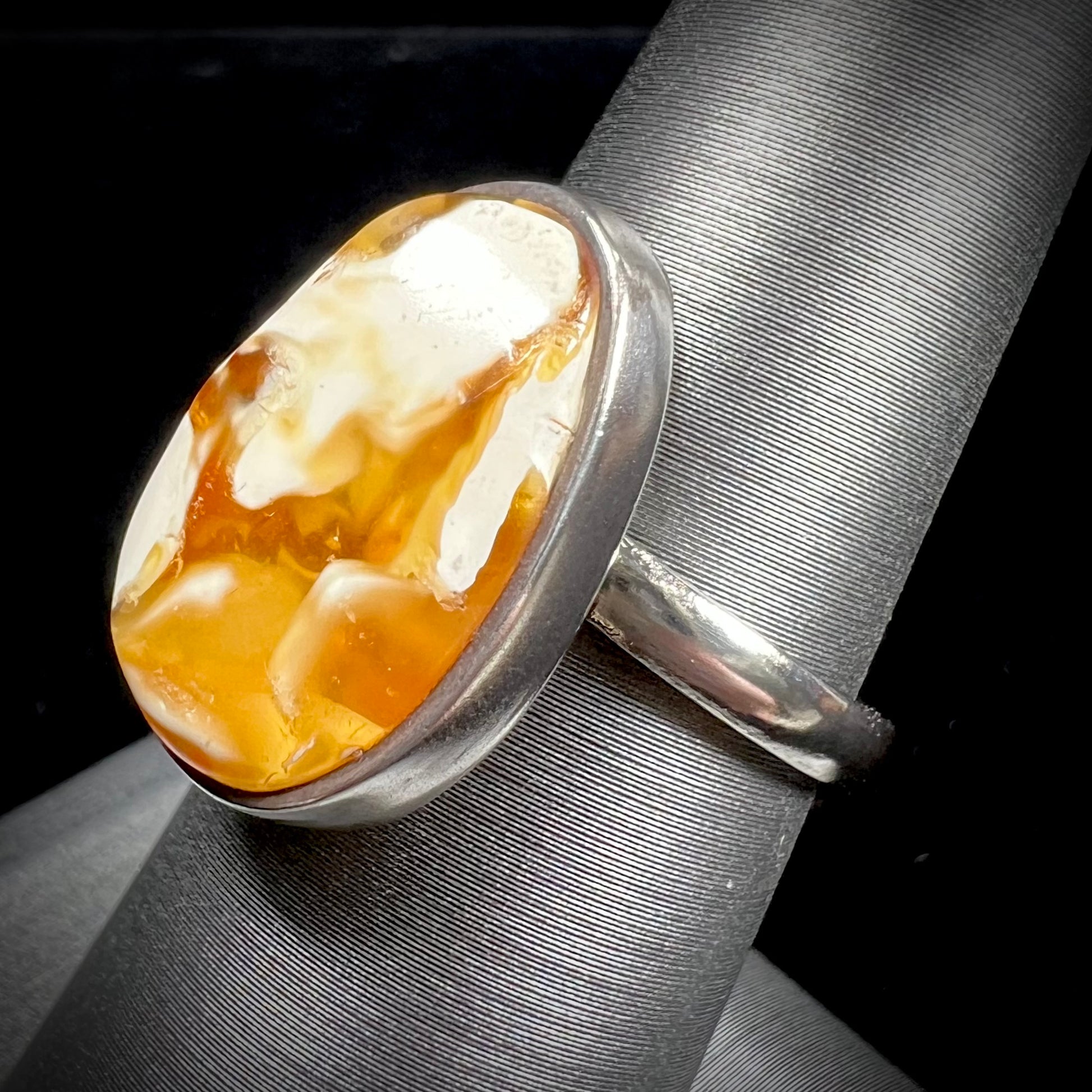 An adjustable sterling silver solitaire ring set with a cabochon cut butterscotch amber stone.