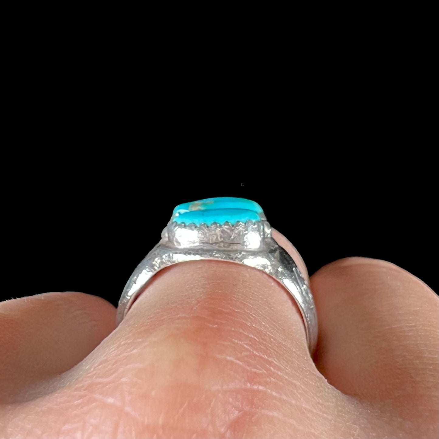 A unisex sterling silver ring bezel set with two Pilot Mountain turquoise stones.  The ring is stamped with sun patterns.